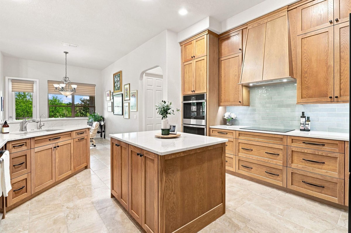 Kitchen island with natural wood cabinetry and drawers overlooking the bright breakfast area in a Roseheart home.