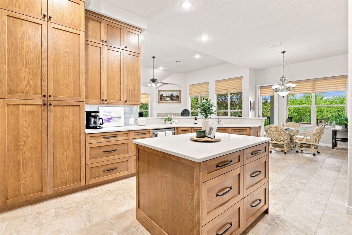 Roseheart kitchen remodel in North Central San Antonio featuring natural wood cabinets, a center island, blue-green tile backsplash, and light countertops.