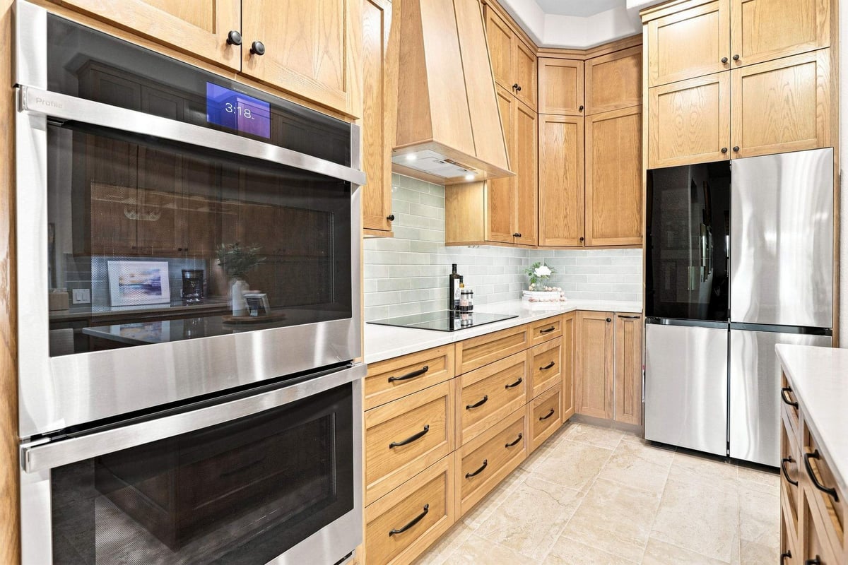 Built-in stainless steel double ovens surrounded by natural wood cabinetry and drawers in a San Antonio kitchen remodel.