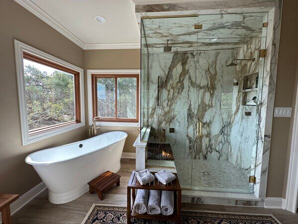 Luxurious bathroom featuring a large glass-enclosed shower with marble walls.