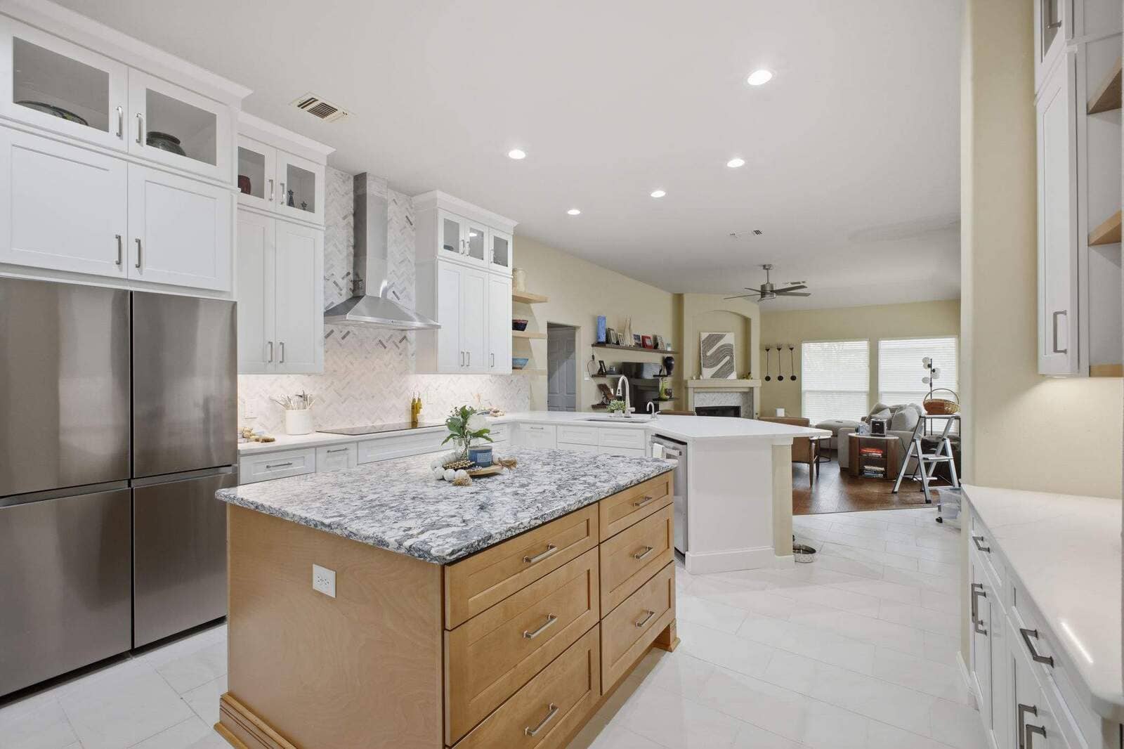 Bright Deerfield kitchen with a wood island, white cabinetry, stainless appliances, and an open living area.