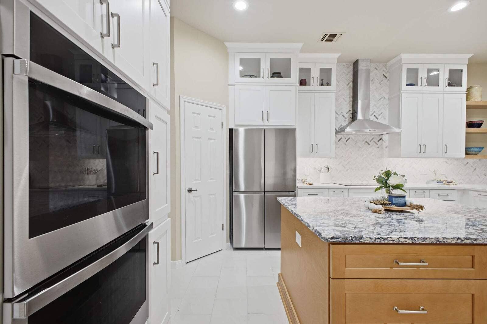 Double wall ovens, white cabinets, and a wood island with stone countertop in a Deerfield kitchen remodel.