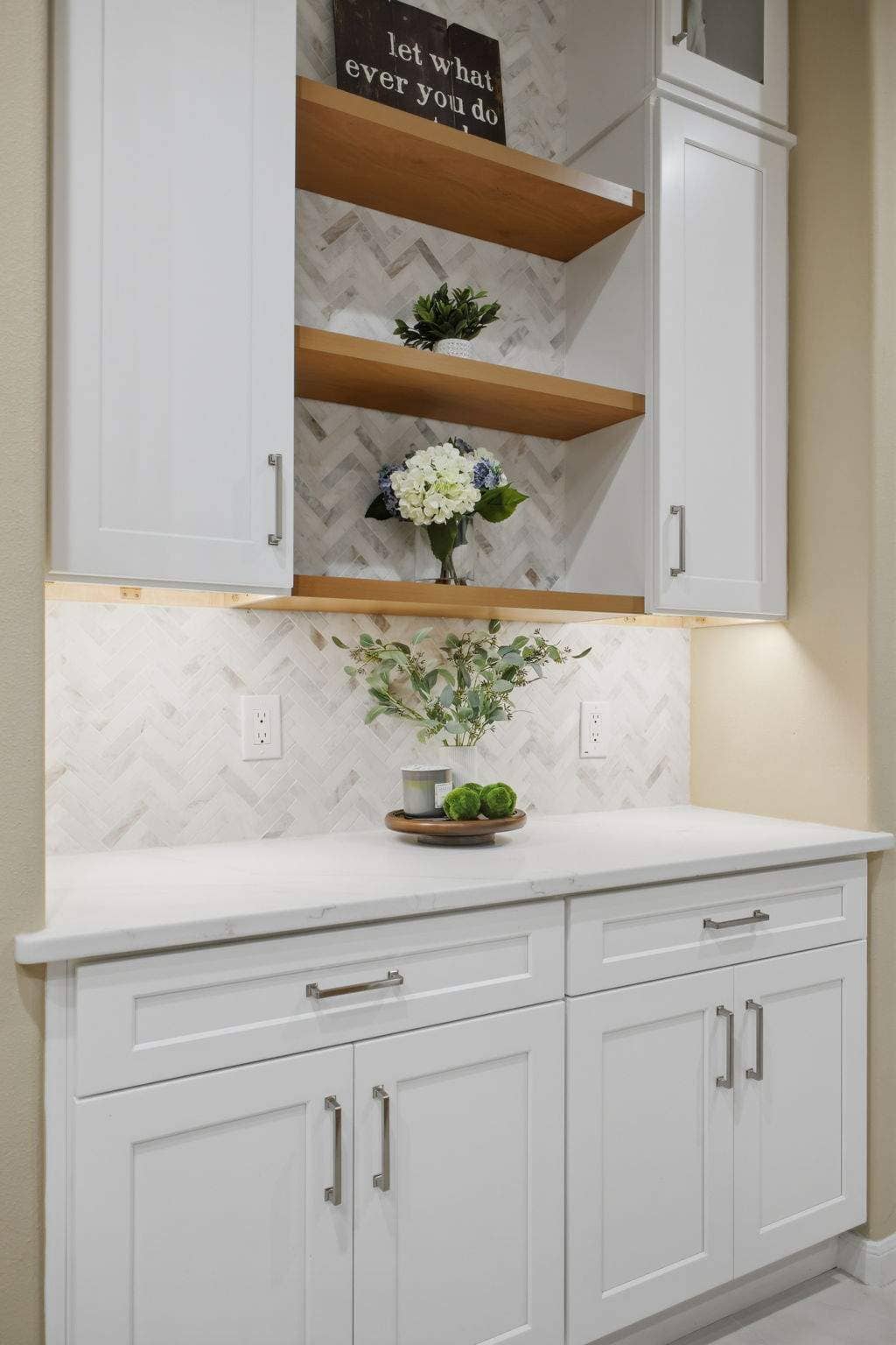 White kitchen hutch with floating wood shelves, quartz counter, and herringbone backsplash in San Antonio.
