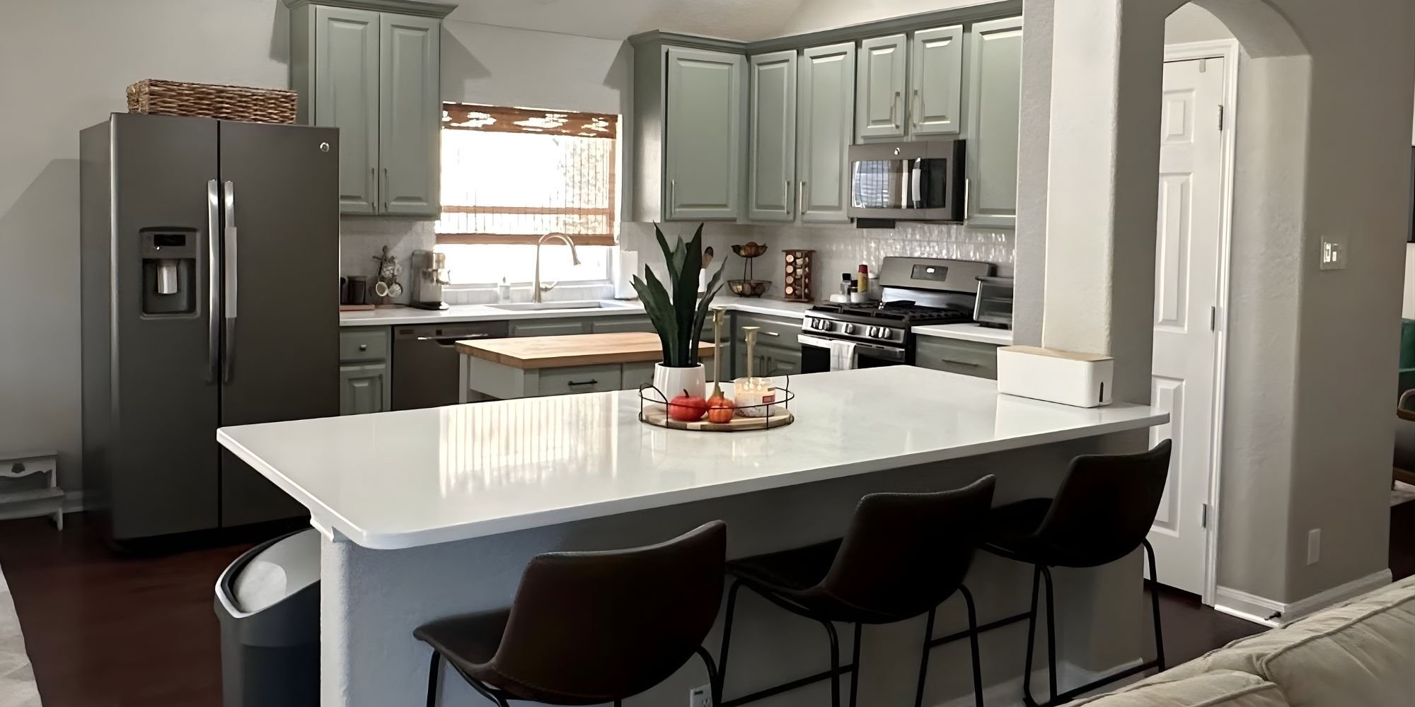 san antonio kitchen renovation with green cabinets and bar stool seating on white countertop