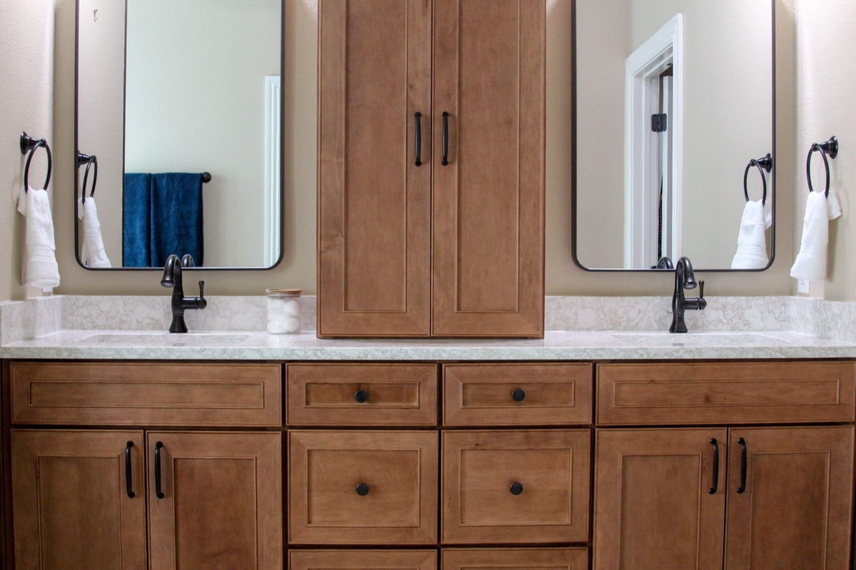 Maple double vanity with center tower, framed mirrors, and white towels