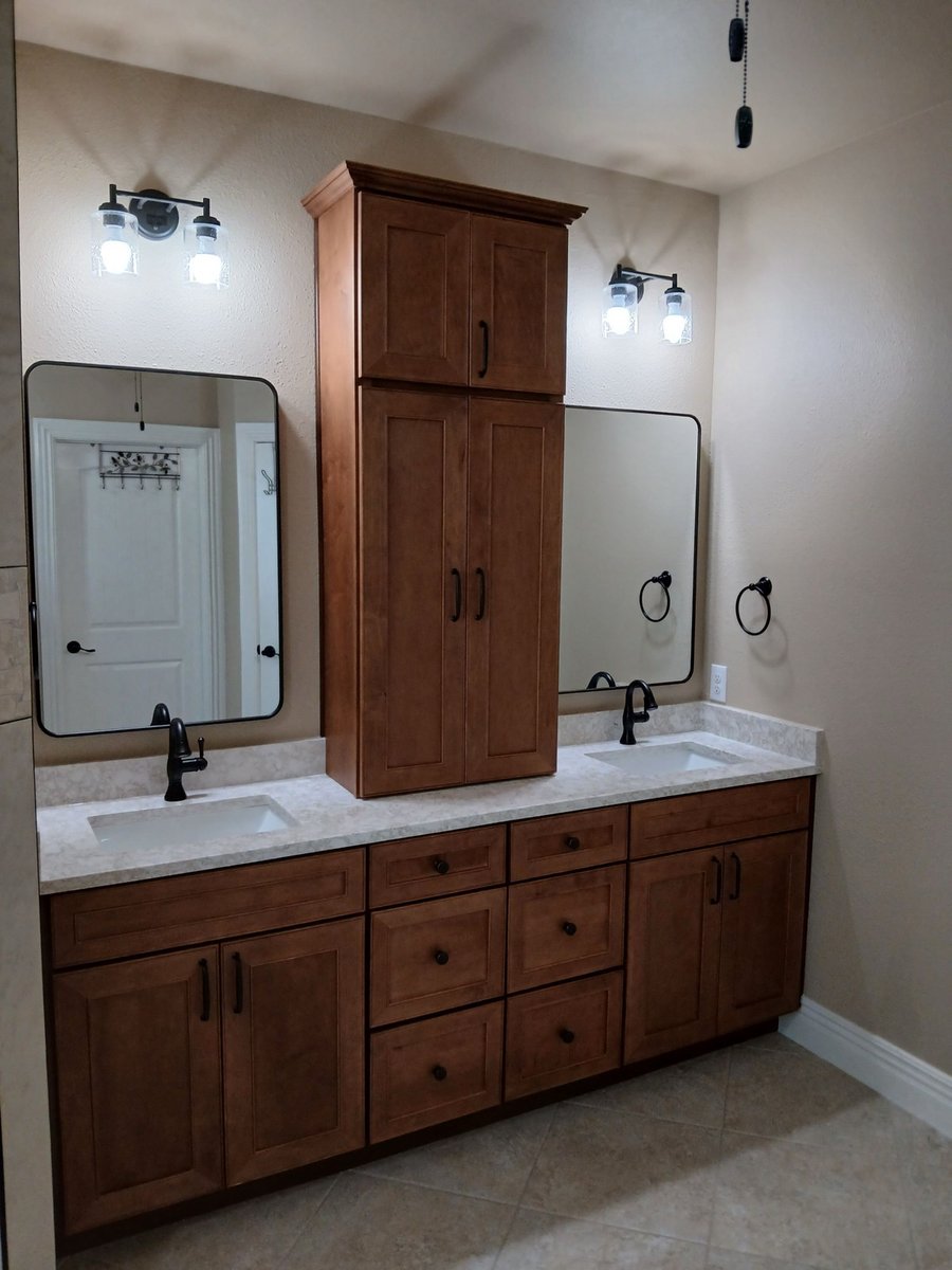 Double vanity in stained maple with center tower, framed mirrors, and black sconces