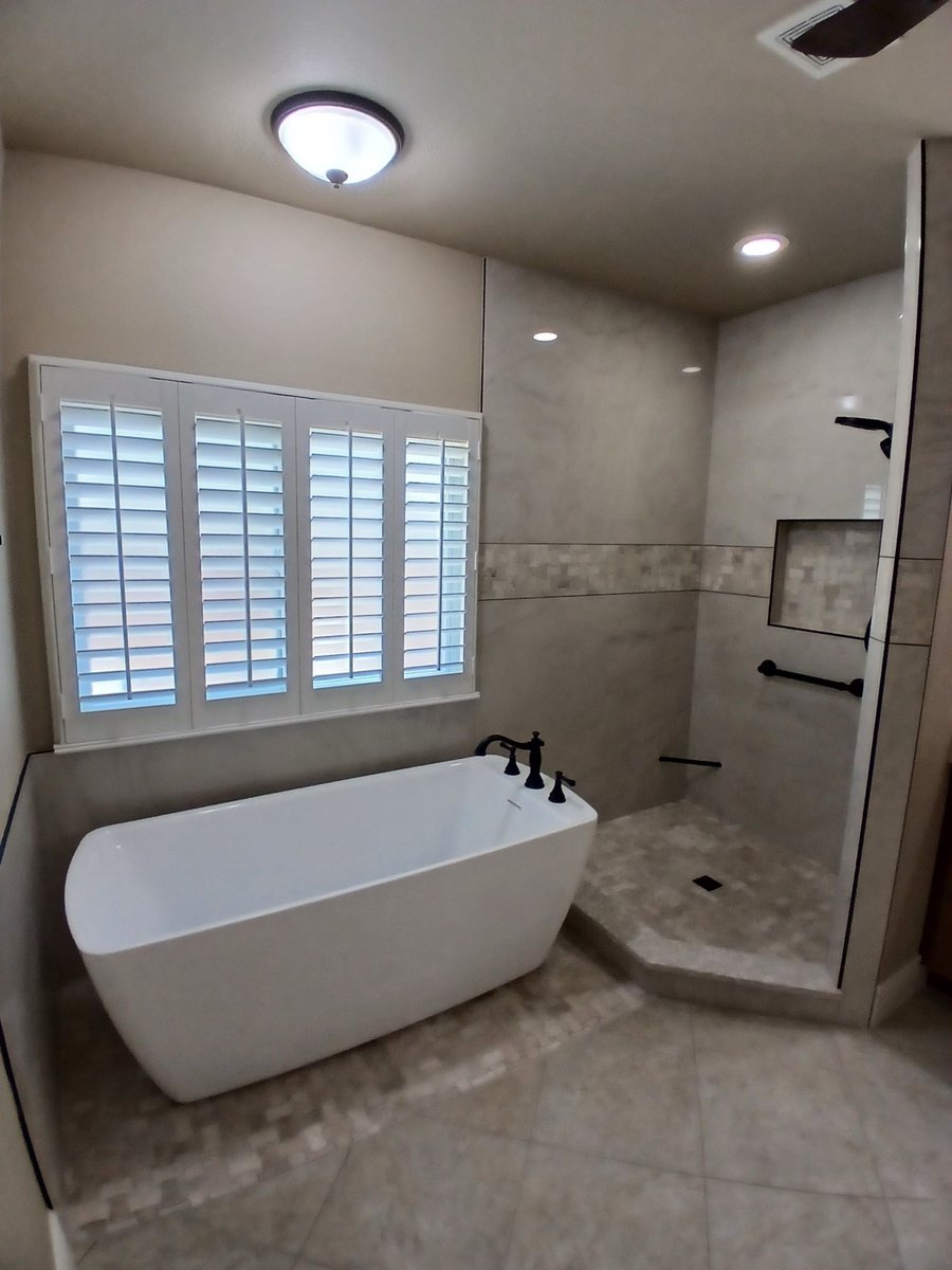 Freestanding tub and open marble walk-in shower with mosaic accent band