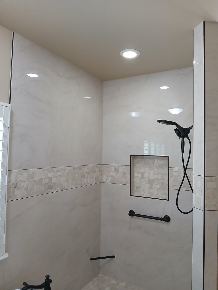 Marble shower wall with basketweave accent niche and oil-rubbed bronze fixtures