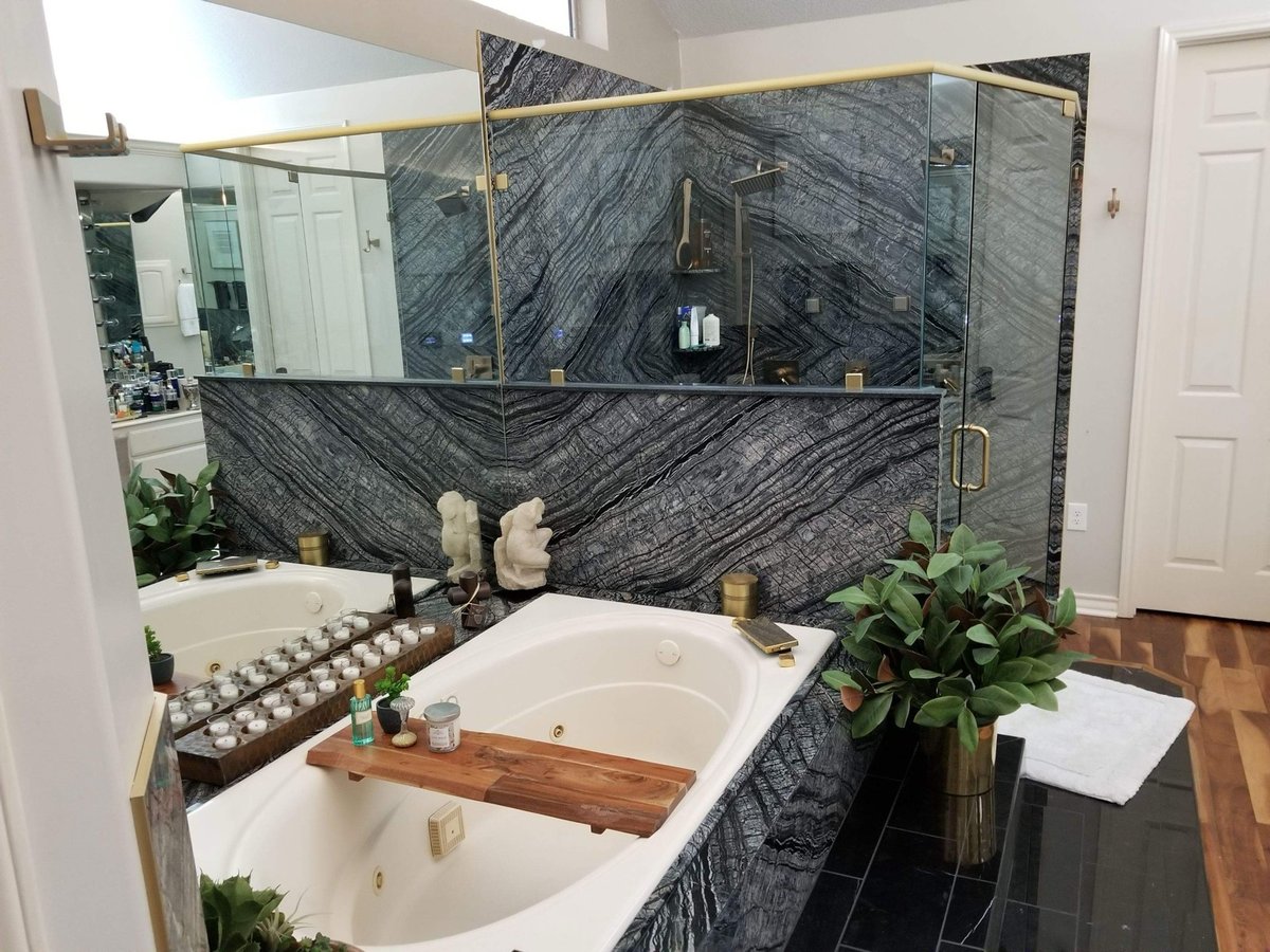 Dramatic black wood-vein stone wall behind soaking tub and glass shower