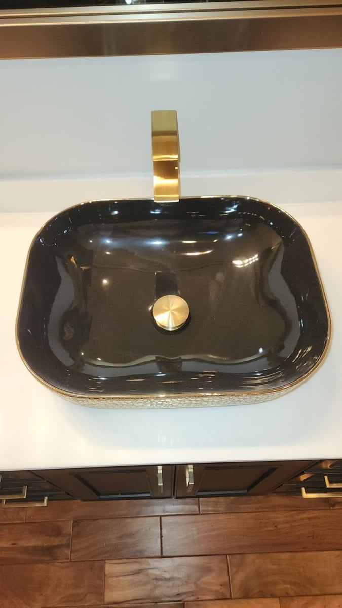 Glossy black and gold vessel sink with gold waterfall faucet
