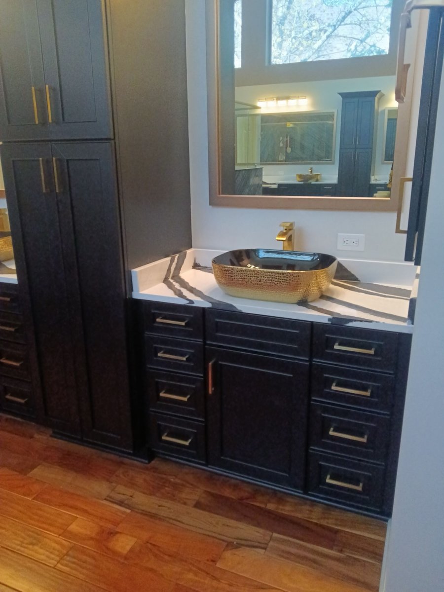 Black vanity with gold hammered vessel sink and dramatic veined countertop