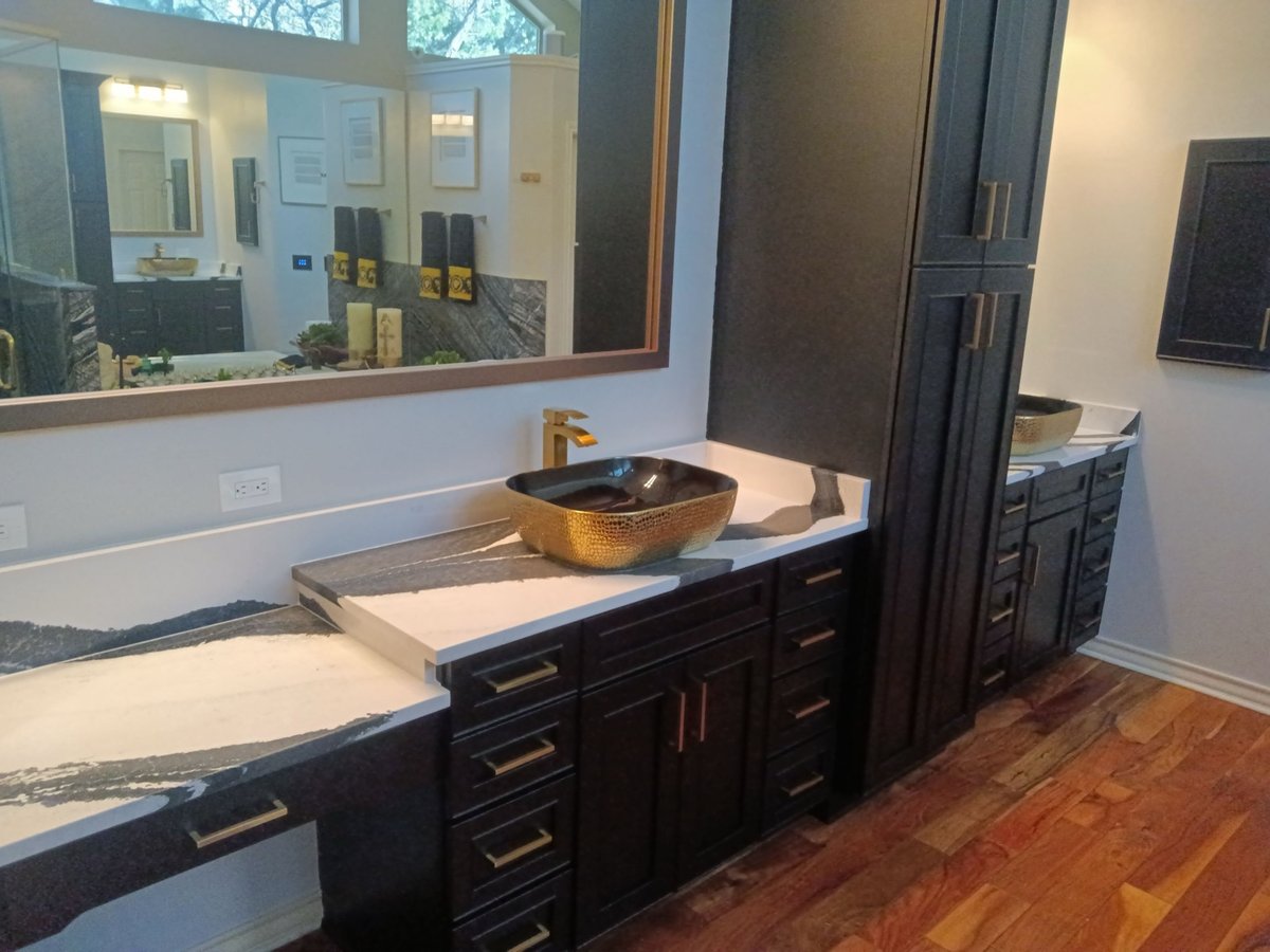 Dual black vanities with gold vessel sinks and bold veined countertops