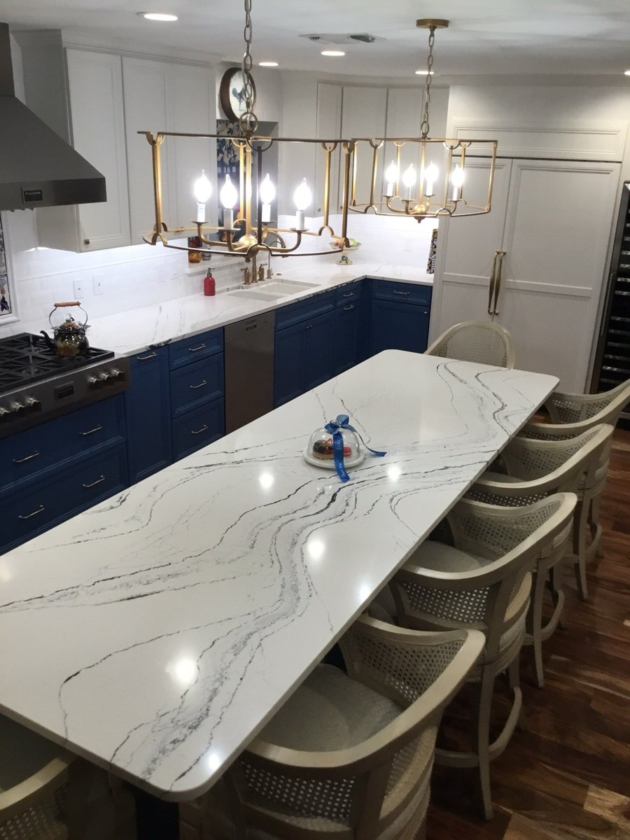 Navy and white kitchen with quartz waterfall island and brass lantern lights