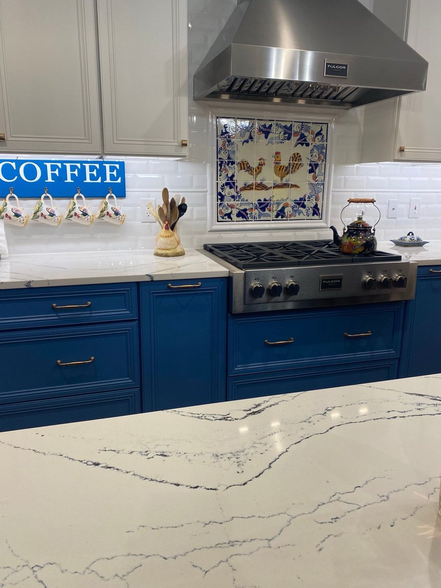 Veined white quartz counter beside gas cooktop and white subway backsplash