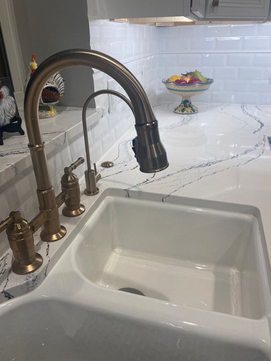 Closeup of gas cooktop edge over veined quartz with tile mural behind
