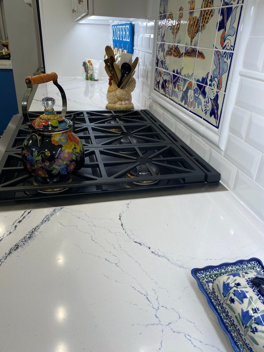 White uppers, navy lowers and stainless hood over gas cooktop on wood floor