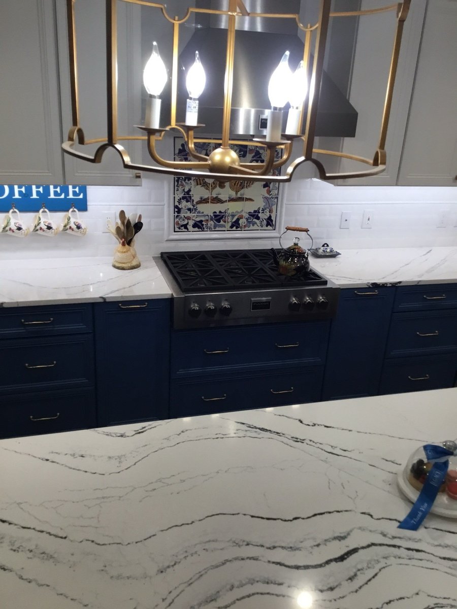 Gas cooktop with painted blue-and-white tile mural and navy lower cabinets