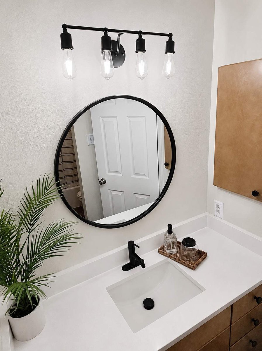 Round black mirror, Edison vanity lights, and white quartz sink over walnut cabinetry