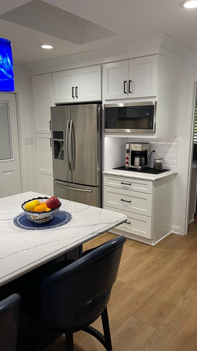 White cabinet wall with stainless refrigerator, microwave, and coffee station