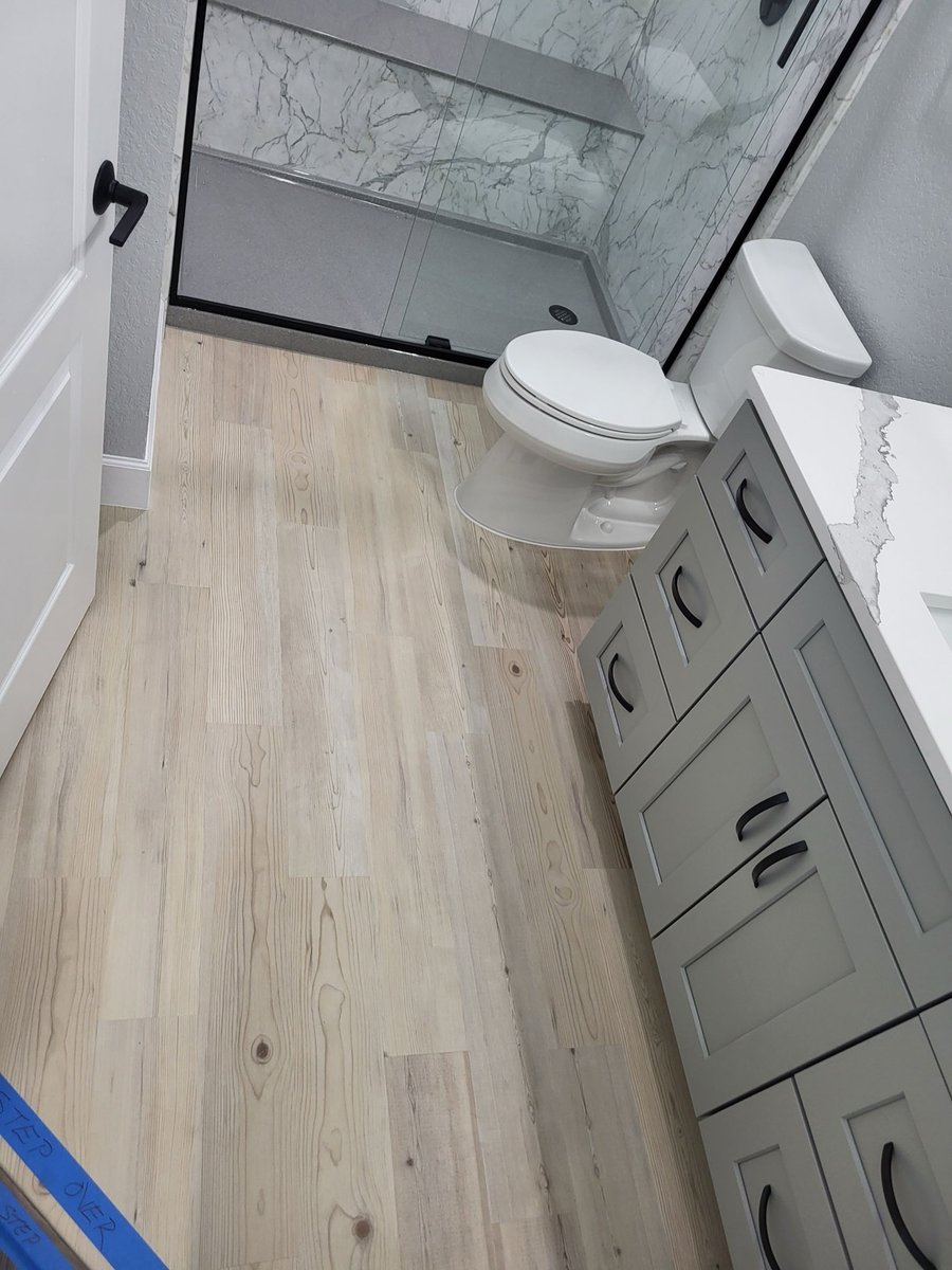 Overhead view of wood-look flooring, gray vanity, and walk-in shower