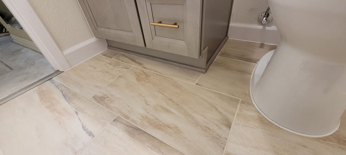 Wood-look porcelain tile floor with gray vanity base and toilet in remodeled bath