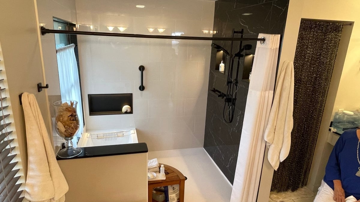 Bathroom with white tub, black marble shower and matte black sliding rod