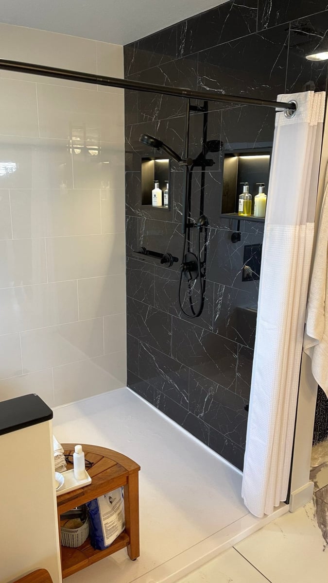 Black marble shower with backlit niches, matte black fixtures and white towels
