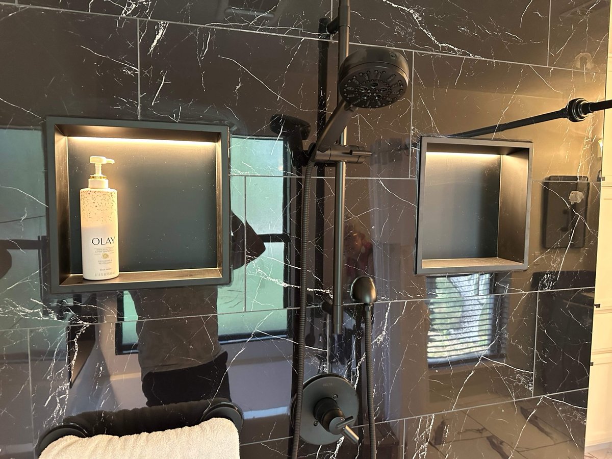 Black marble shower wall with lit niches, black rain head and handheld sprayer