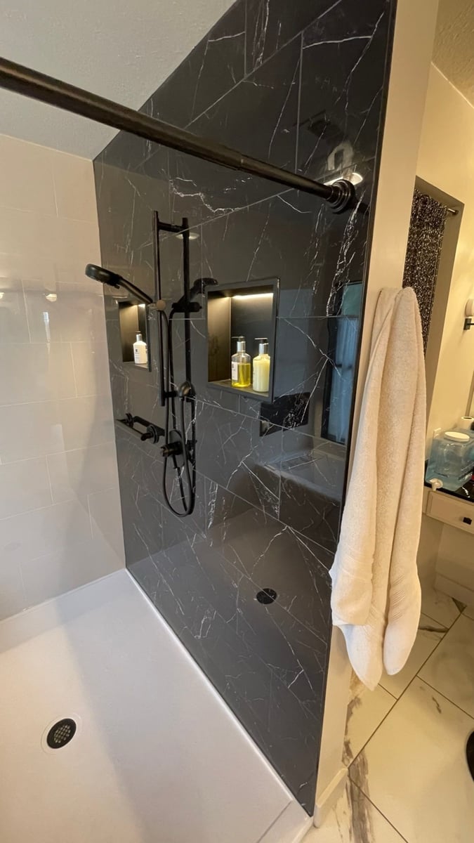 Black marble shower with lit niches, bench seat and matte black sprayer system