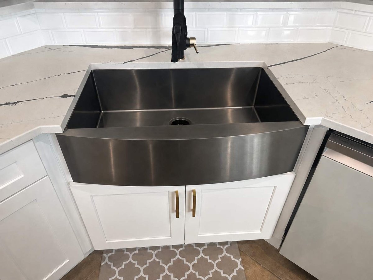 Stainless steel apron-front farmhouse sink set in veined white quartz counter