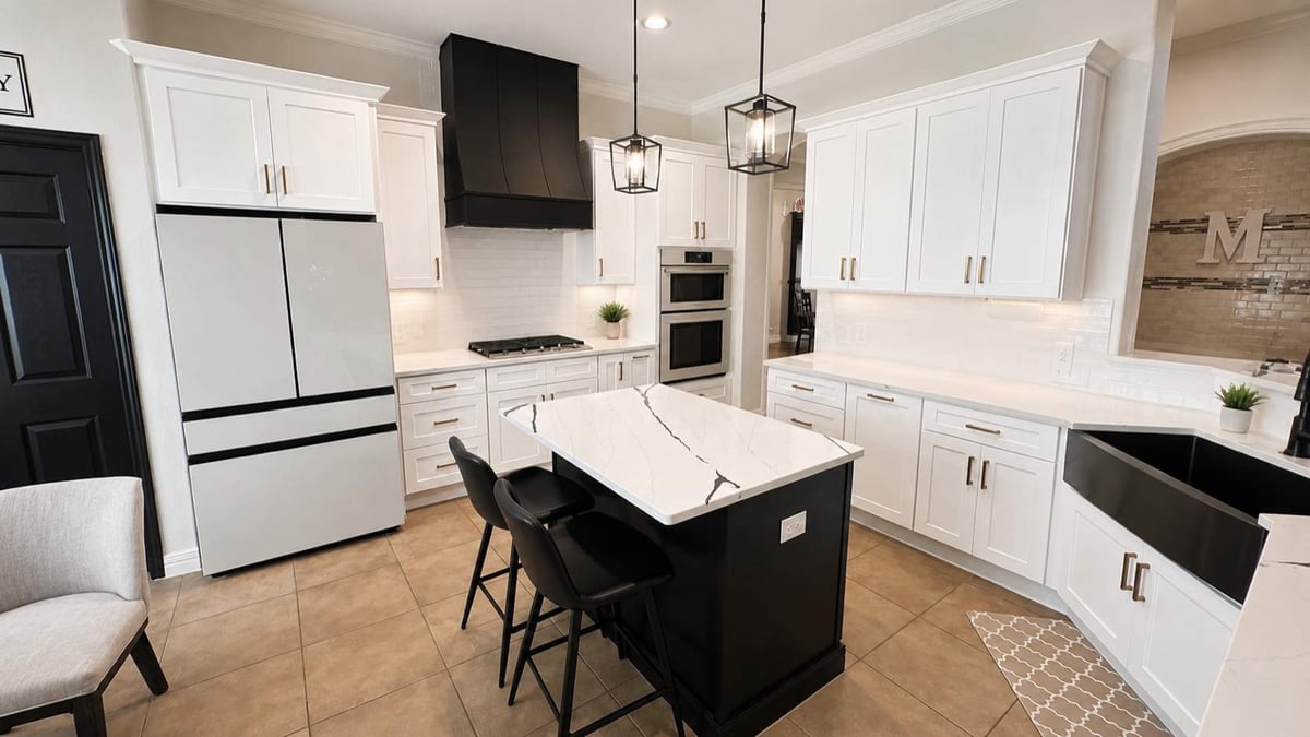 Open white kitchen with black quartz-topped island and pendant lighting