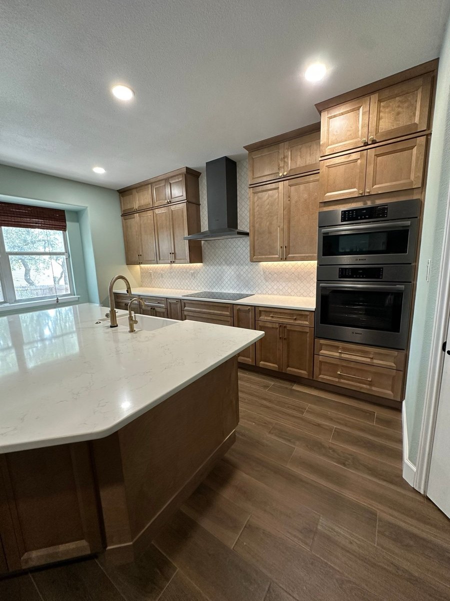 Kitchen with quartz island, window above sink and black Bosch double wall ovens