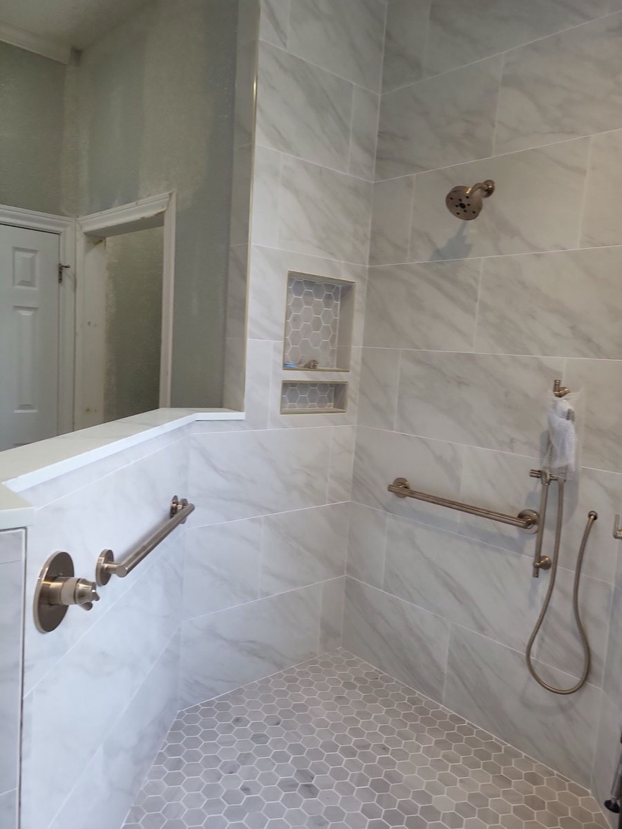 Curbless walk-in shower with grab bars and hexagon marble floor tile