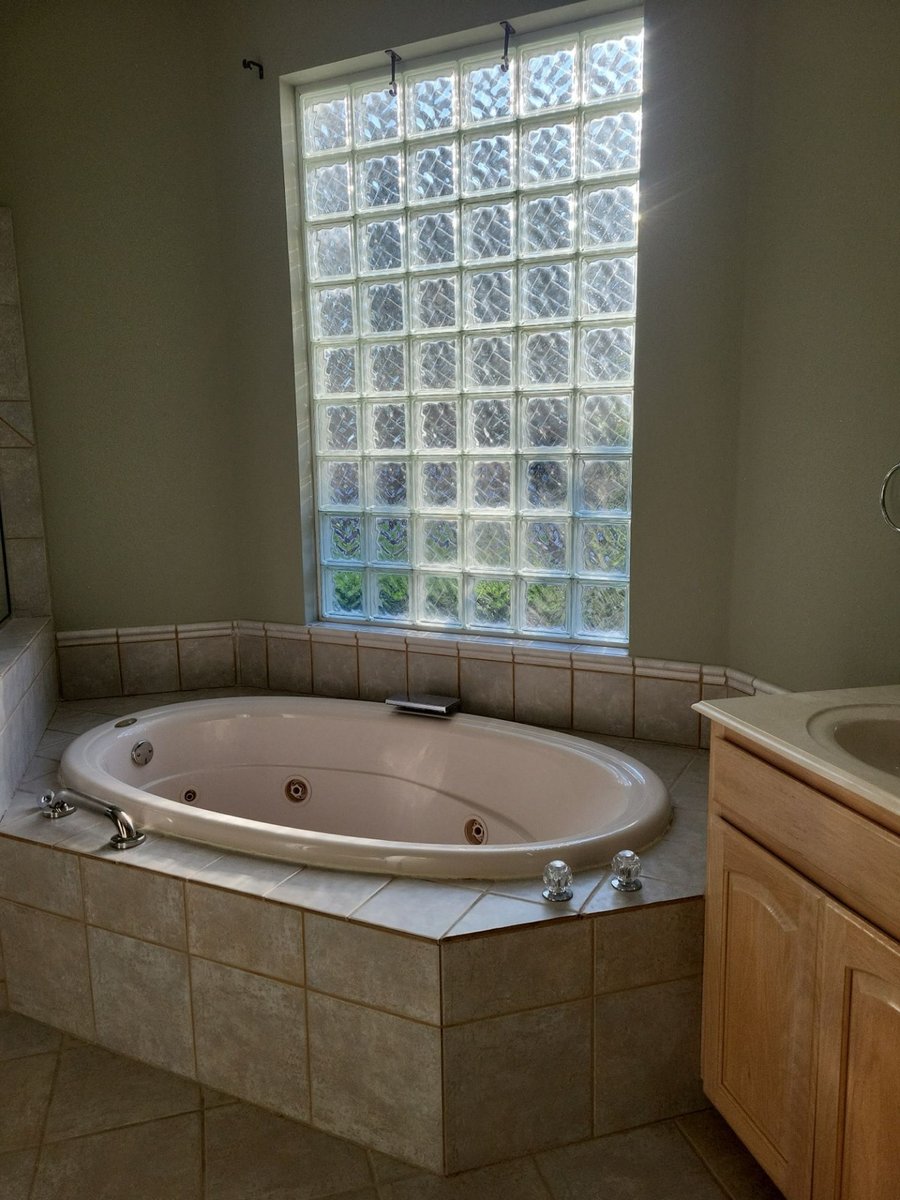 Original oval jetted garden tub under glass block window before the remodel