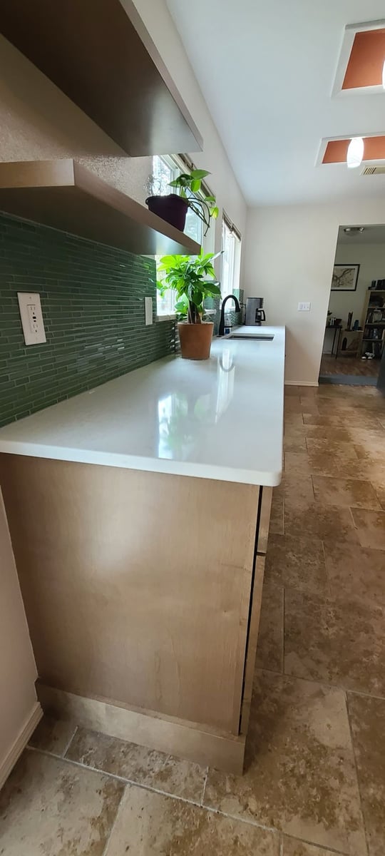 Peninsula counter with green glass tile backsplash and floating wood shelf