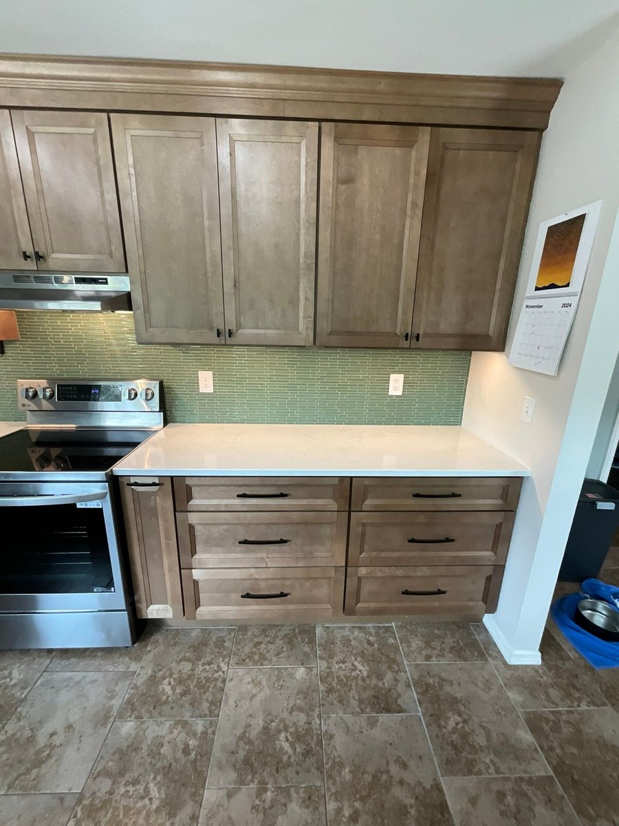 Maple cabinets with green glass backsplash flanking a stainless range