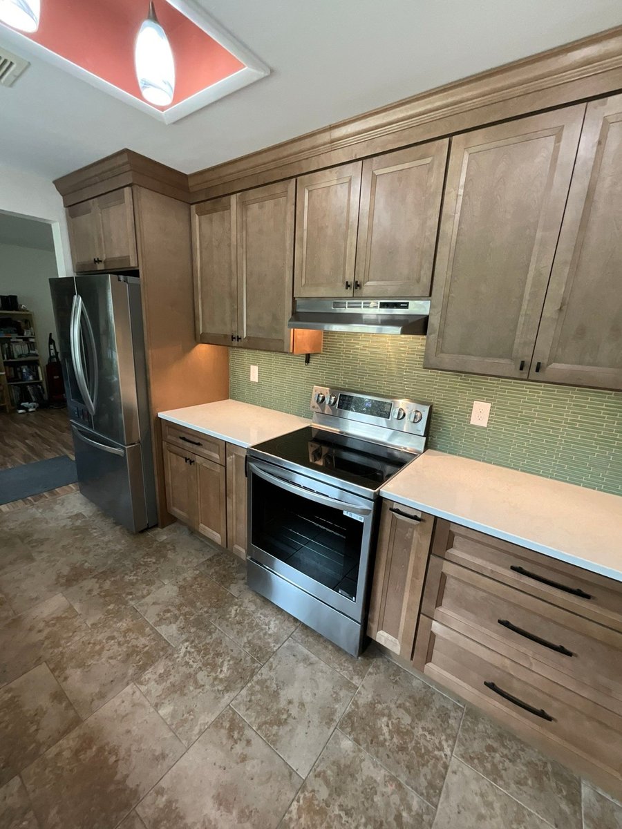 Maple kitchen with stainless range, French-door fridge and travertine floor