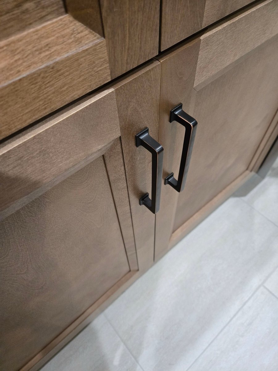 Closeup of stained wood shaker cabinets with oil-rubbed bronze handles
