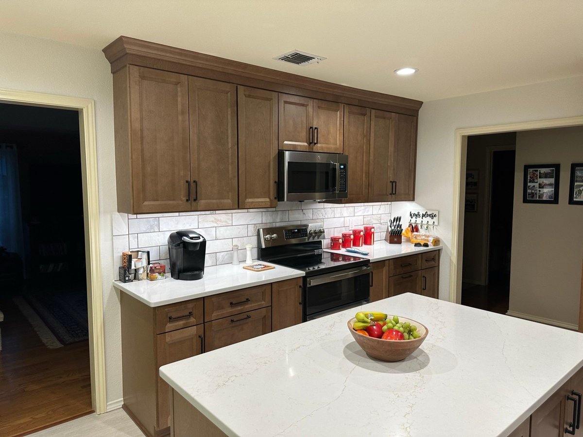 Remodeled kitchen with stained wood cabinets, white quartz island and bar seating