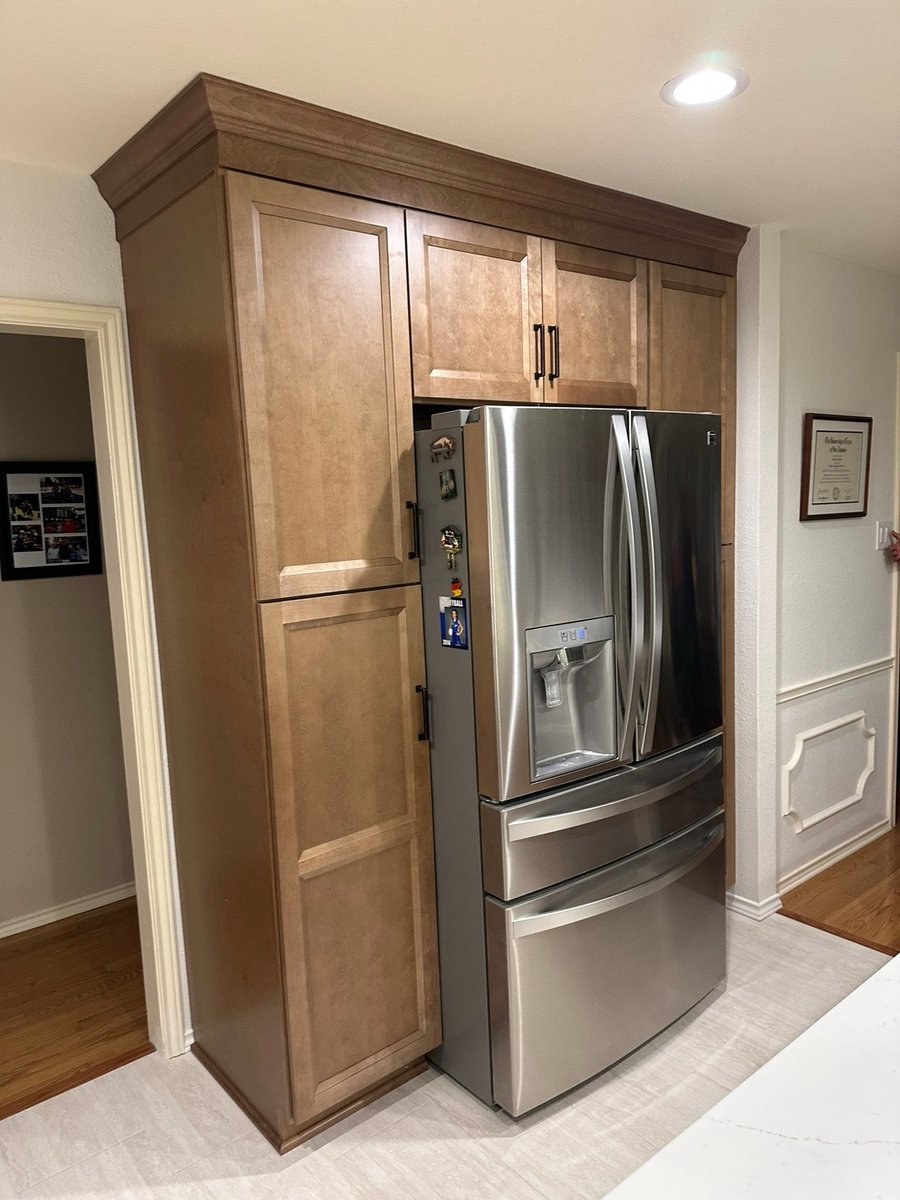 Tall wood pantry cabinet built around stainless French-door refrigerator