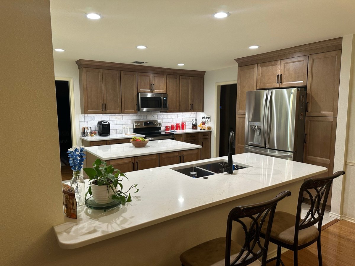 Wood cabinet kitchen with quartz peninsula bar and stainless range