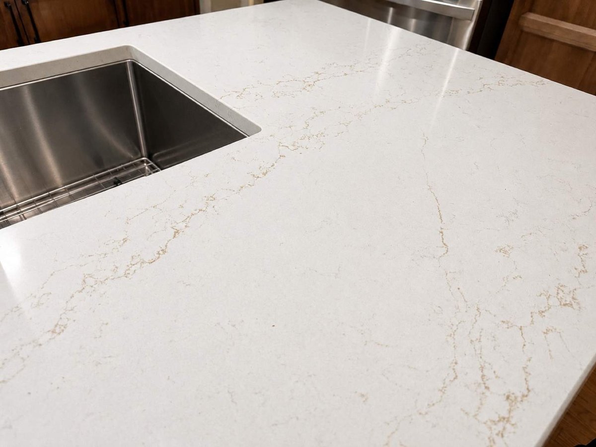 Stainless undermount sink in veined white quartz island countertop