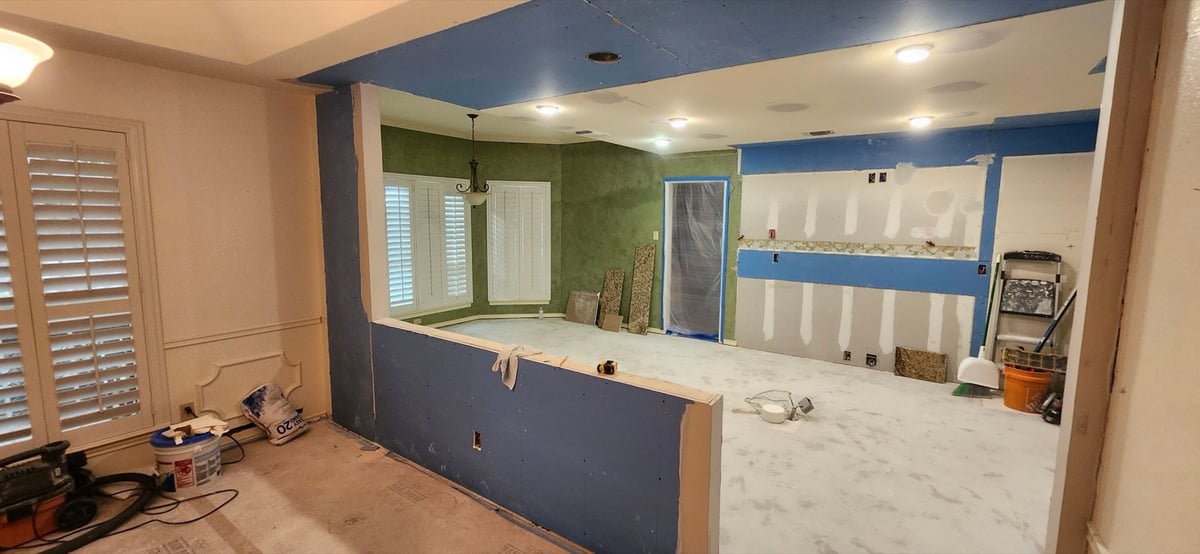 Stripped kitchen under construction with green walls and concrete subfloor