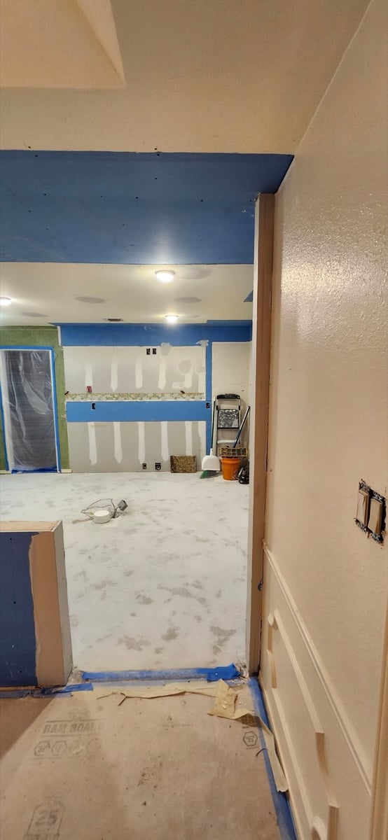 Unfinished kitchen with patched drywall, blue ceiling and bare subfloor