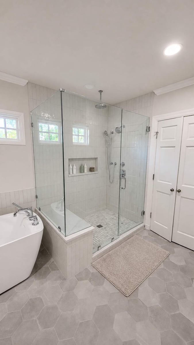 White freestanding tub and corner glass shower with niche and white double doors