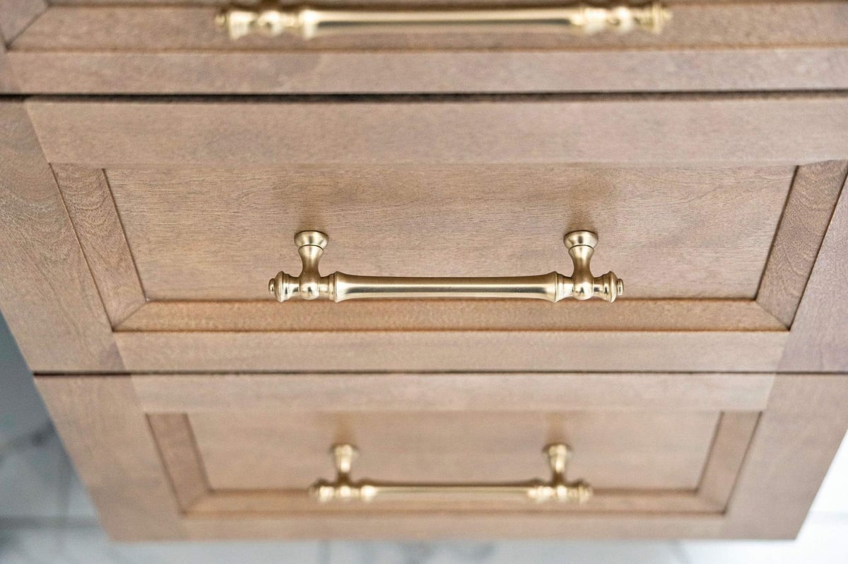 Close-up of warm wood bathroom cabinetry with elegant brass drawer pulls in a Rogers Ranch primary bathroom remodel in San Antonio.