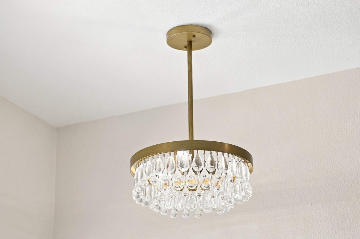Decorative crystal chandelier with brass accents above a freestanding soaking tub in a Rogers Ranch primary bathroom remodel in San Antonio.