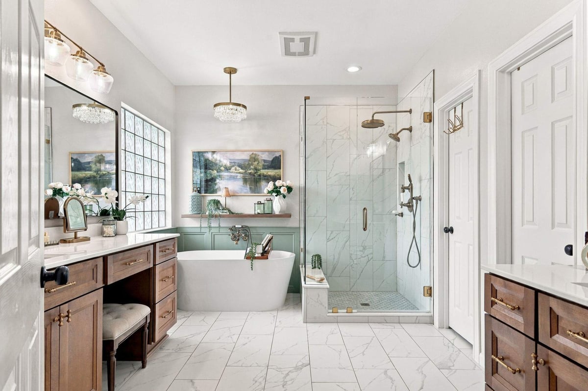 Freestanding soaking tub and walk-in shower in a Rogers Ranch primary bathroom remodel featuring wood vanities and brass fixtures.