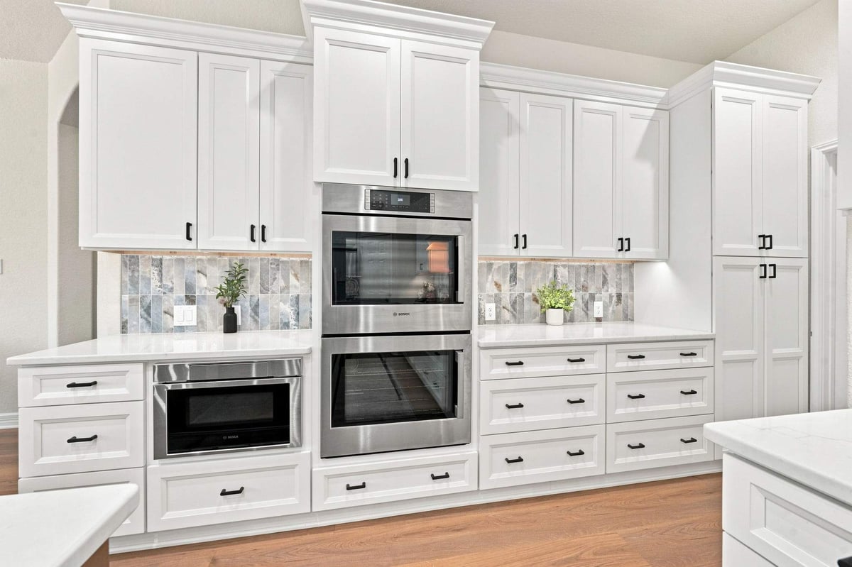 Cibolo Canyons kitchen remodel in San Antonio featuring floor-to-ceiling white cabinetry, built-in stainless steel appliances, deep drawers, and black hardware.