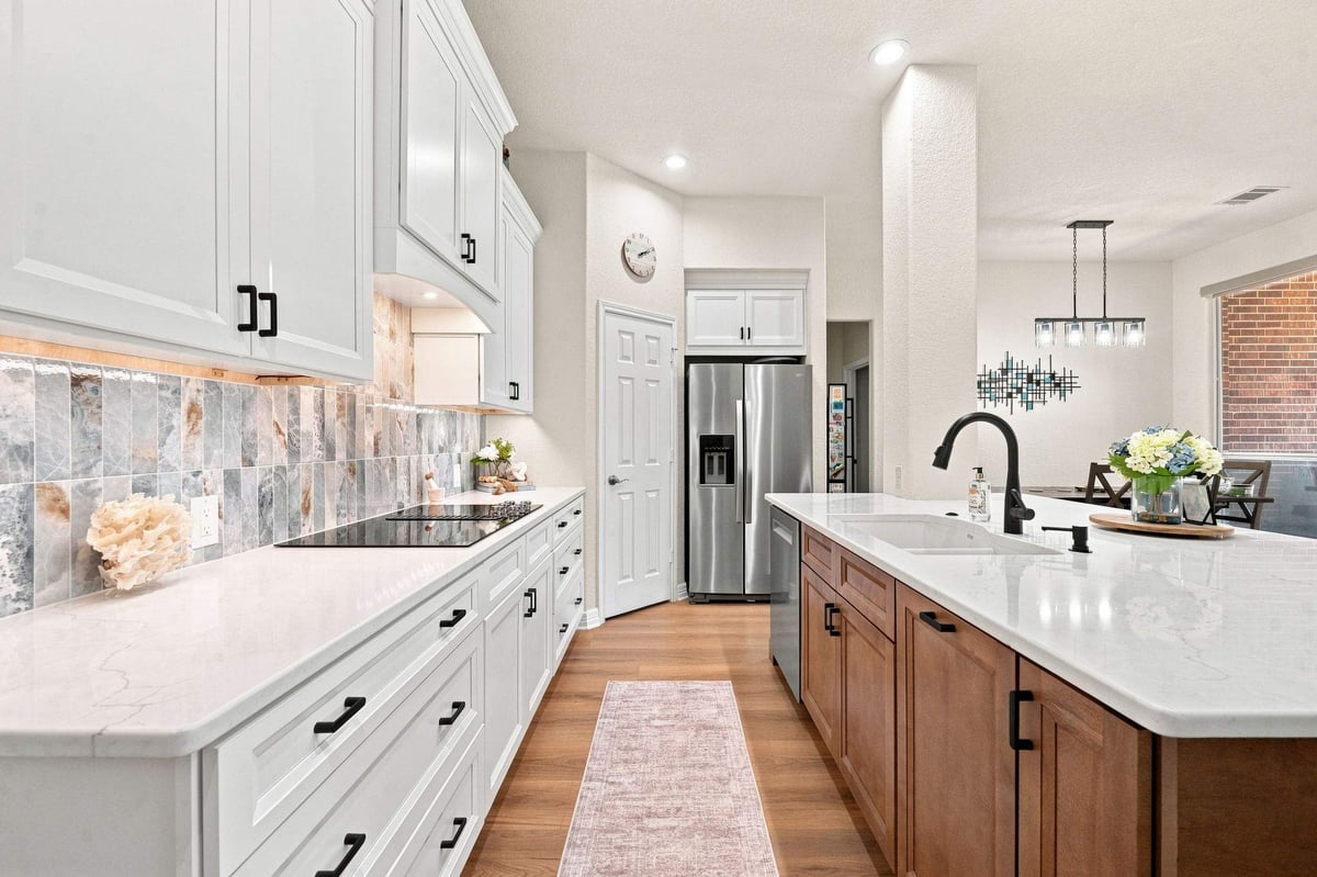 Cibolo Canyons kitchen remodel featuring recessed lighting above a large wood island, white shaker-style cabinetry, and decorative tile backsplash.